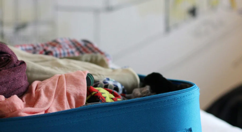 A close-up of clothes packed tightly into a blue travel bag